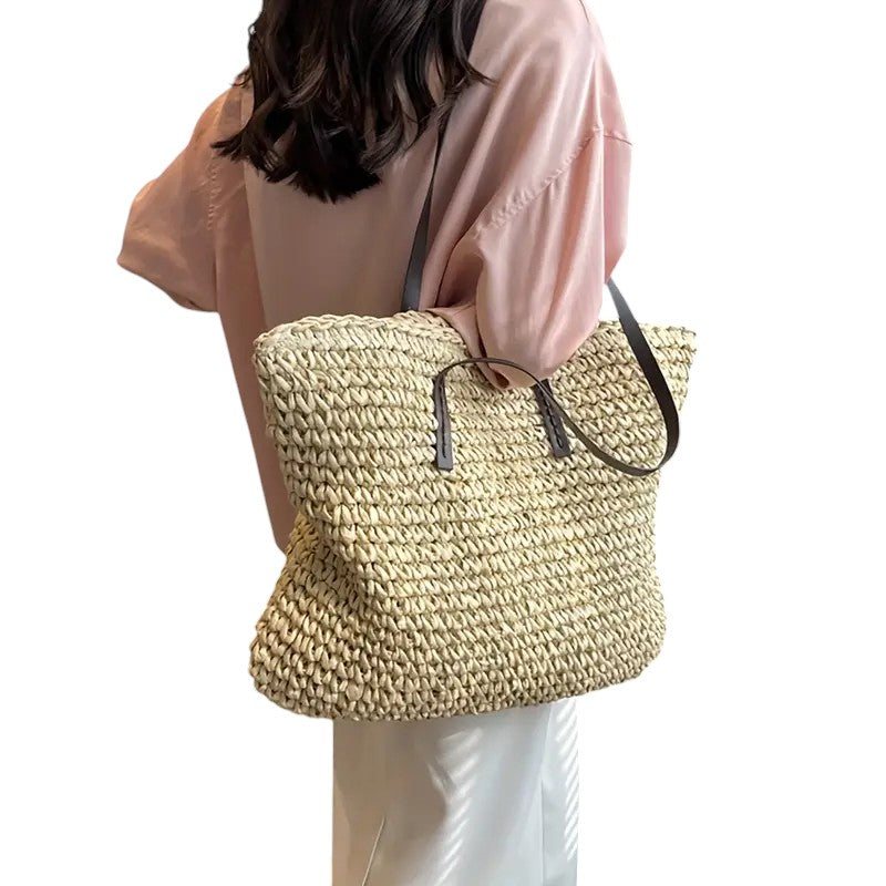 Borsa tote intrecciata Adele verde, posata su una superficie chiara, con un libro e occhiali all'interno.
