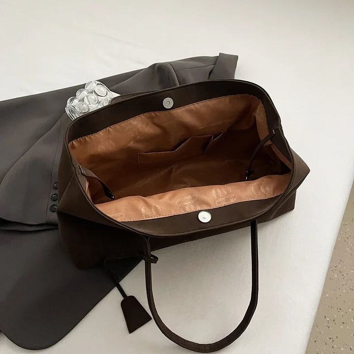 Primo piano del manico della borsa tote Arianna nera, con enfasi sul comfort e sulla robustezza.
