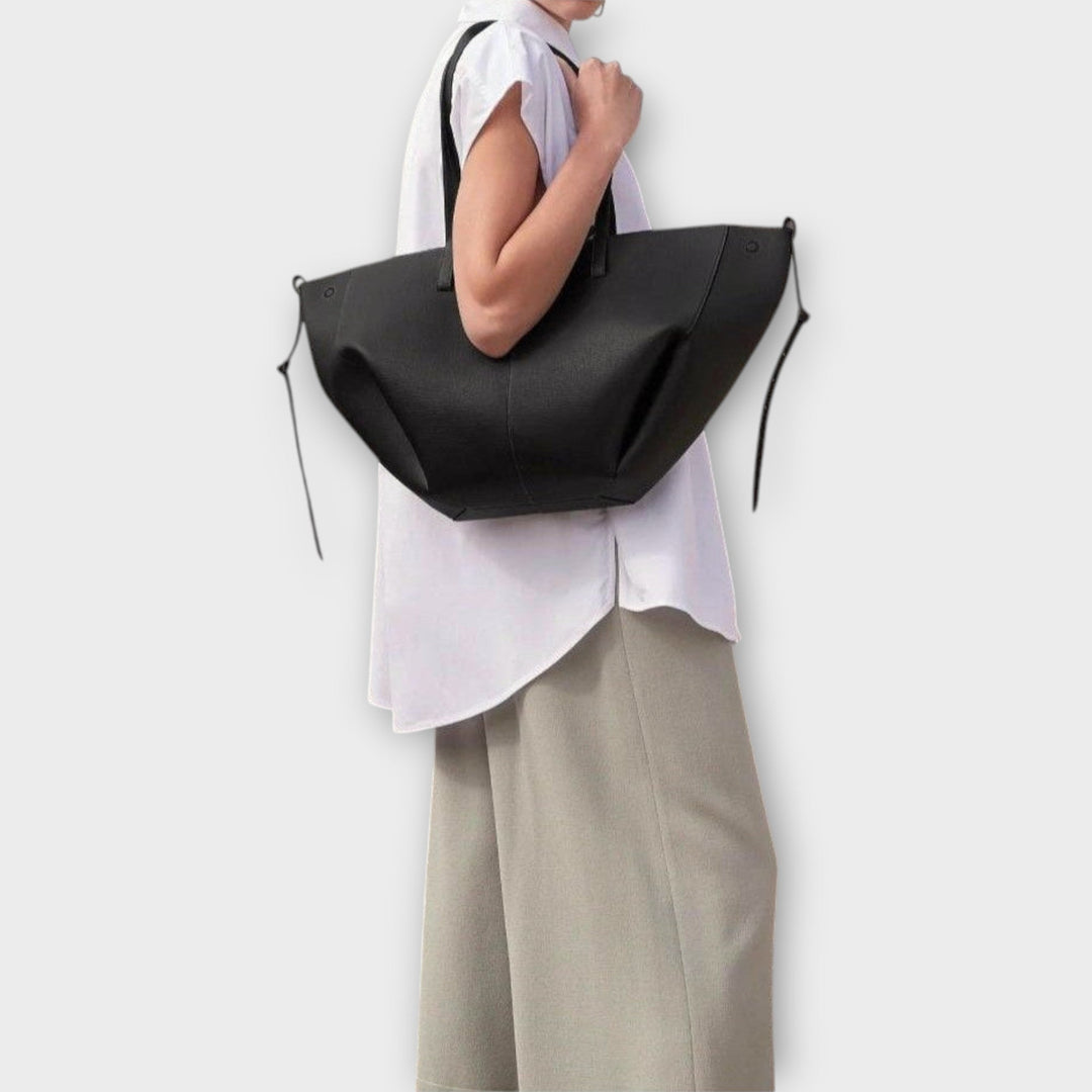 Borsa Aura color marrone chiaro su uno sfondo chiaro, evidenziando il design raffinato.