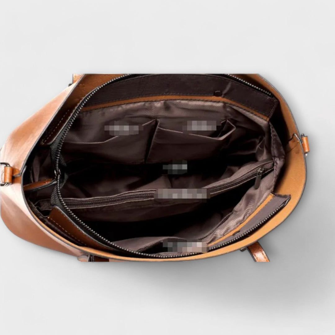 Donna che tiene in mano la borsa a spalla Aurelia, primi piani sui dettagli dei manici e della finitura.