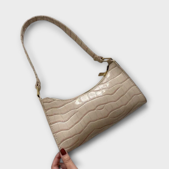 La borsa Bianca marrone, appoggiata su una sedia, ideale per un outfit autunnale o invernale.