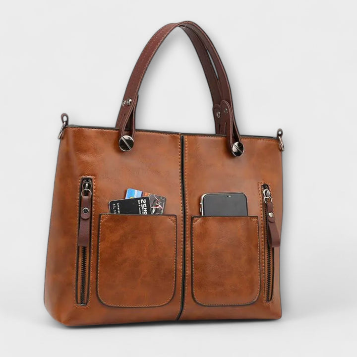 Borsa Cassia in pelle grigia indossata a spalla da una donna, in un contesto urbano, evidenziando la versatilità.