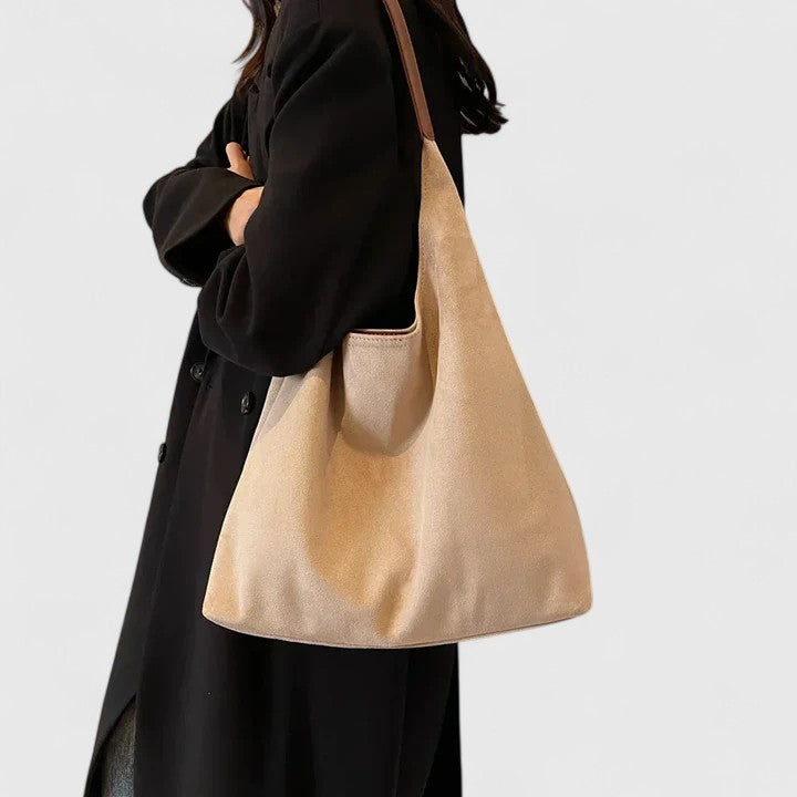 Modella che indossa la borsa Cassia verde a spalla, in un contesto urbano elegante