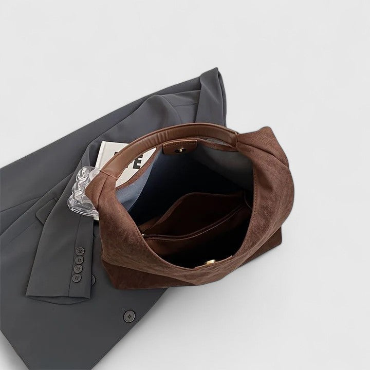 La borsa Cassia beige posizionata su un tavolo, con accessori personali all'interno