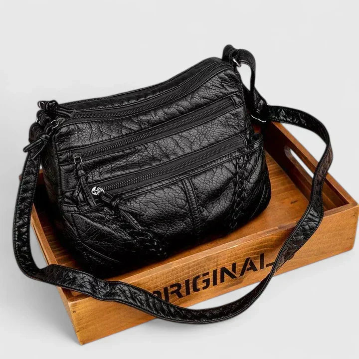 Donna elegantemente vestita che indossa la borsa in pelle Clara a tracolla, in un contesto urbano.