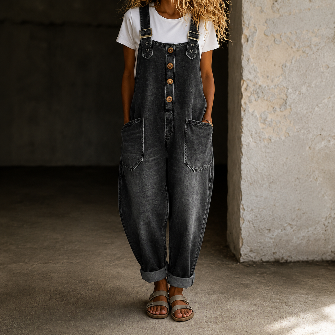 Modella seduta comodamente indossando la tuta Clarissa in denim, evidenziando la vestibilità ampia e rilassata.