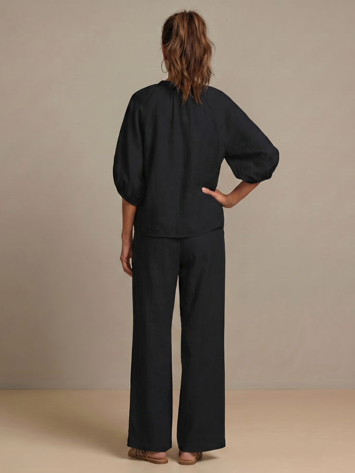Pantaloni a gamba larga Cleo neri, abbinati a sandali e accessori minimalisti.