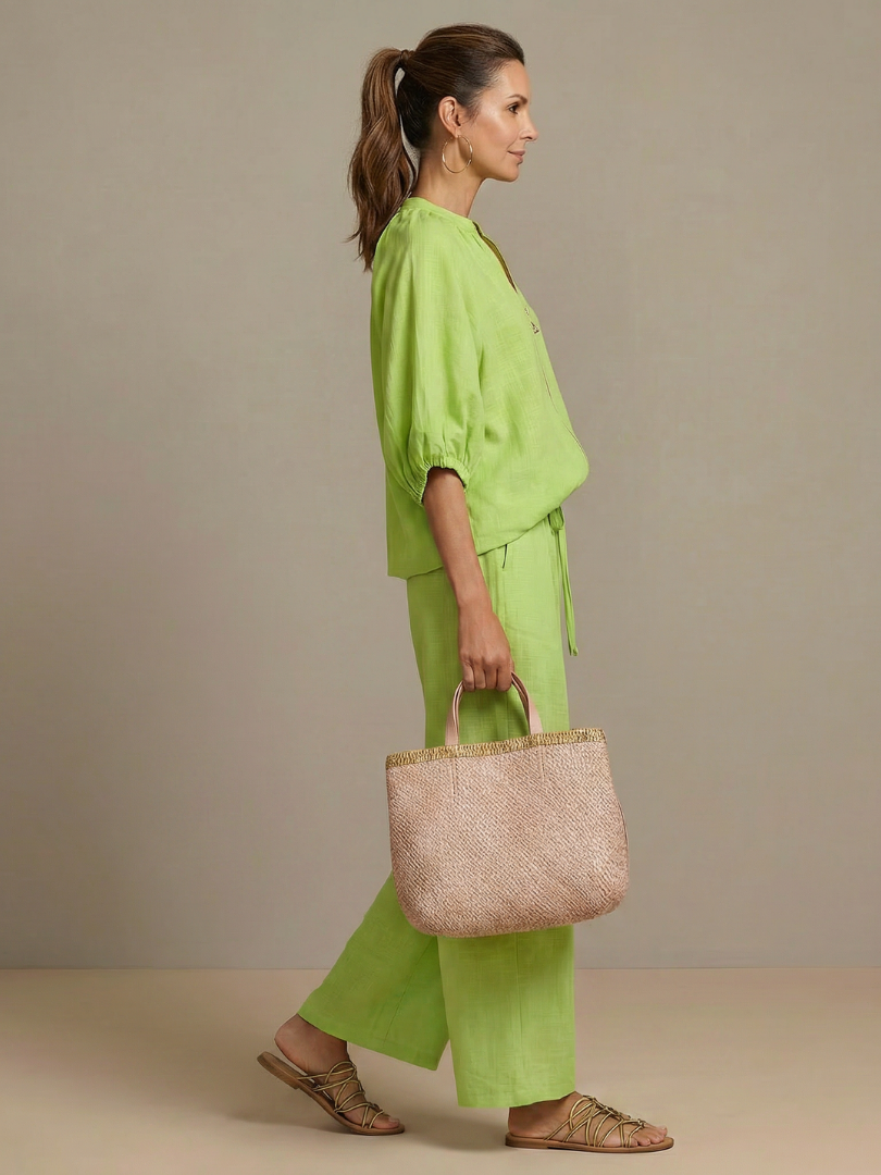 Pantaloni a gamba larga Cleo di profilo, colore verde, con focus sulla caduta del tessuto.