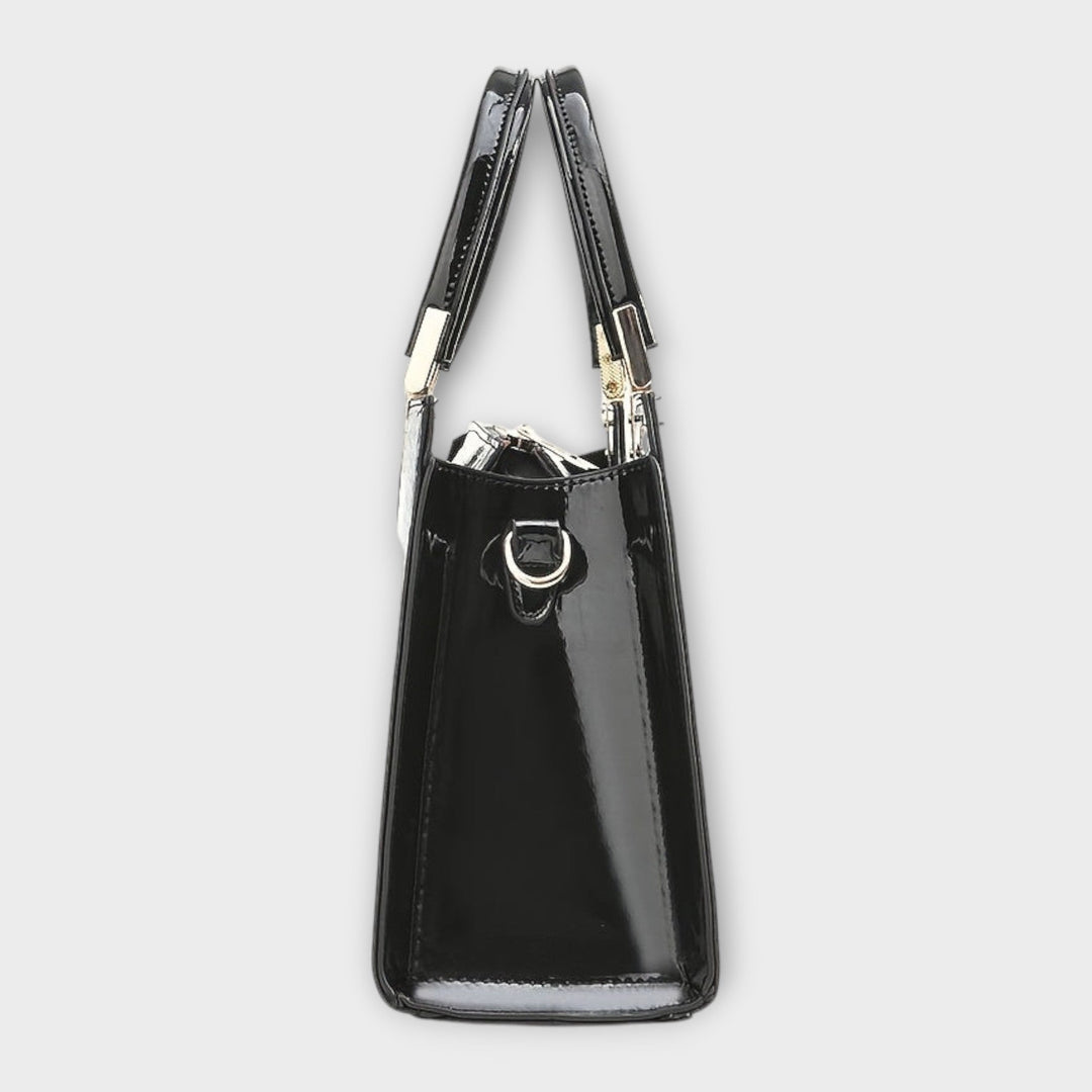 Borsa con motivo coccodrillo lucido di colore marrone, portata a spalla da una modella in ambiente urbano.