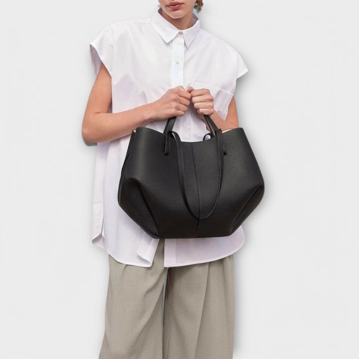 Modella che tiene la borsa Ella nera a mano, mostrando la comodità e il comfort dell'impugnatura.