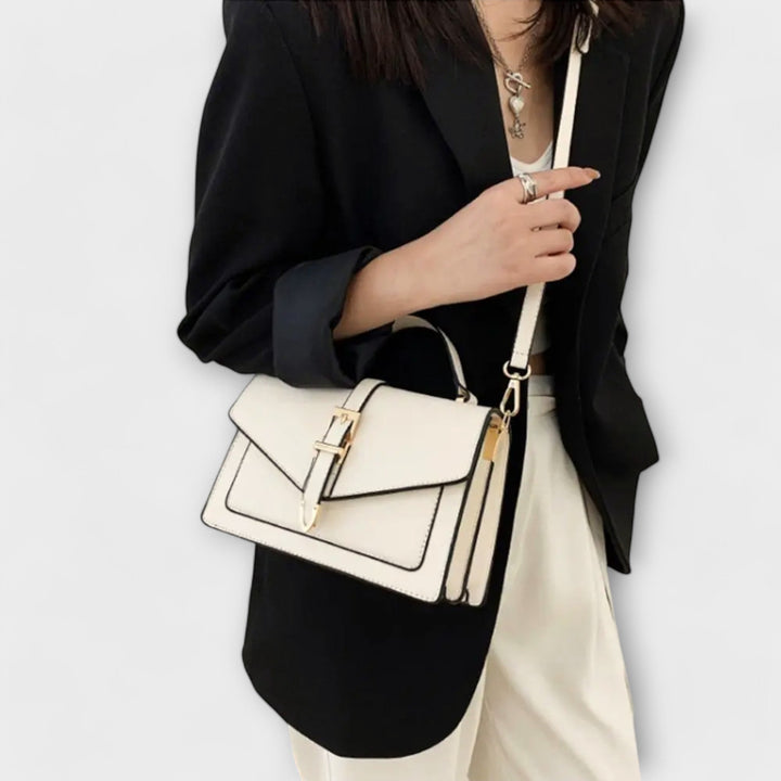 La borsa a spalla Esmée in colore bianco, indossata da una modella, che ne evidenzia la vestibilità e le dimensioni in un contesto urbano.