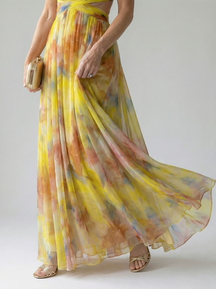 Model draagt de veelkleurige Fleur maxi wikkeljurk, zittend in een ontspannen pose, toont het comfort.