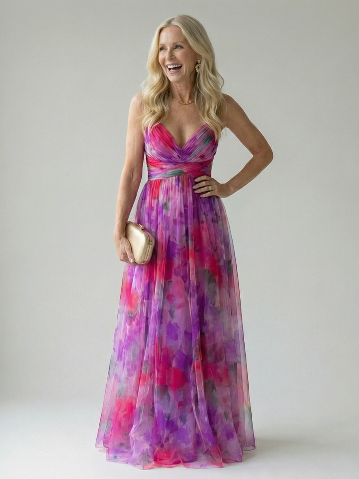 Model in de roze Fleur maxi wikkeljurk, van opzij gefotografeerd, met een focus op de taille en de rok.