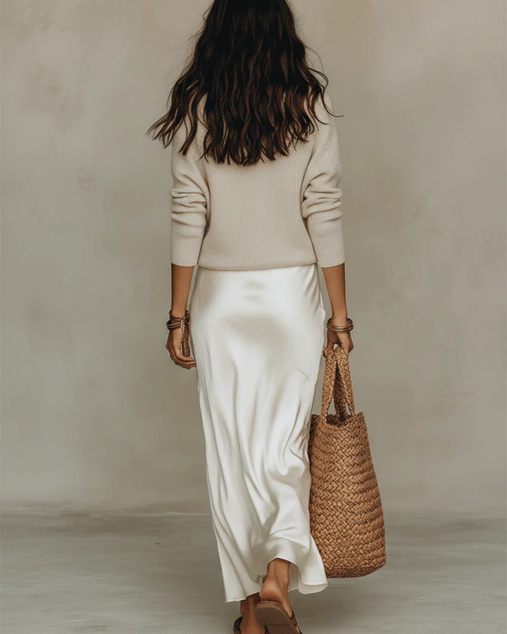 Modella che posa con l'abito midi in raso Gaia bianco, evidenziando la sua silhouette femminile e raffinata.