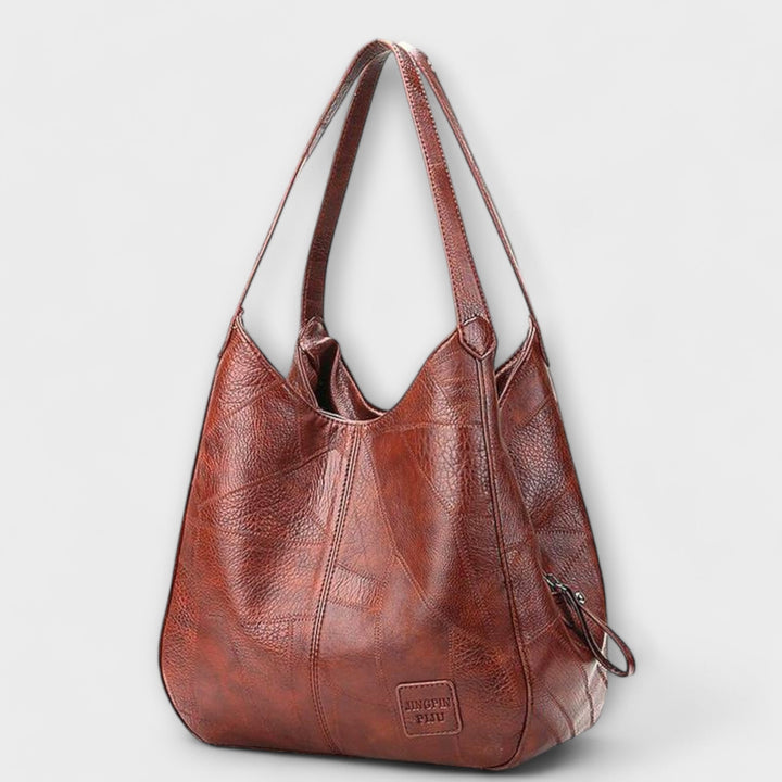 Vista frontale della borsa in pelle vintage Greta, che mostra la sua forma classica e i manici robusti.