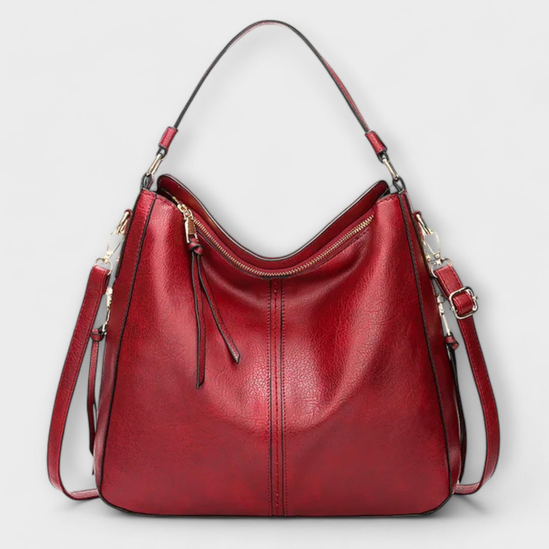 Borsa Indira rossa, in primo piano, con un leggero sfocato sullo sfondo, per far risaltare il colore vivace e il design.