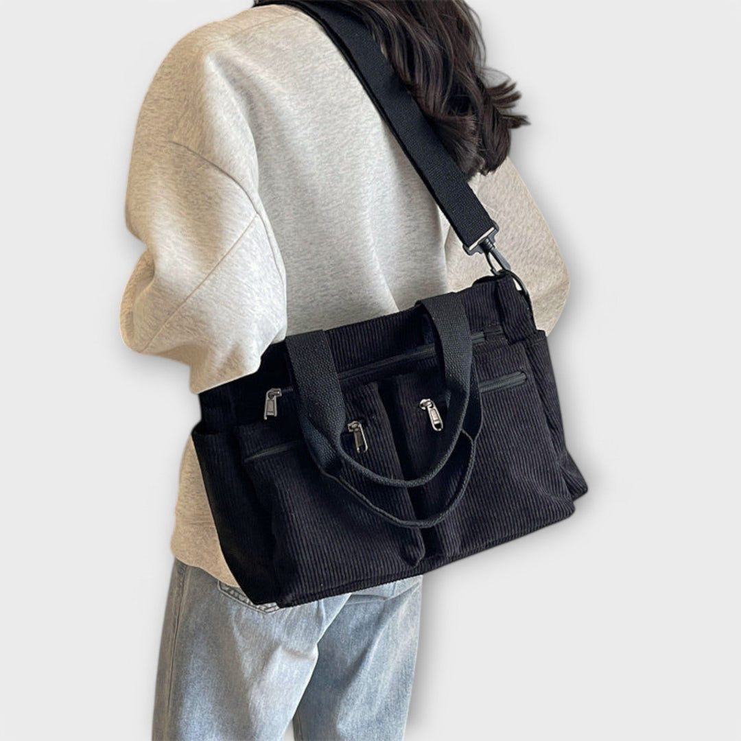 Una serie di borse tote Iris in diverse colorazioni (nero, verde, marrone) allineate, per confronto.