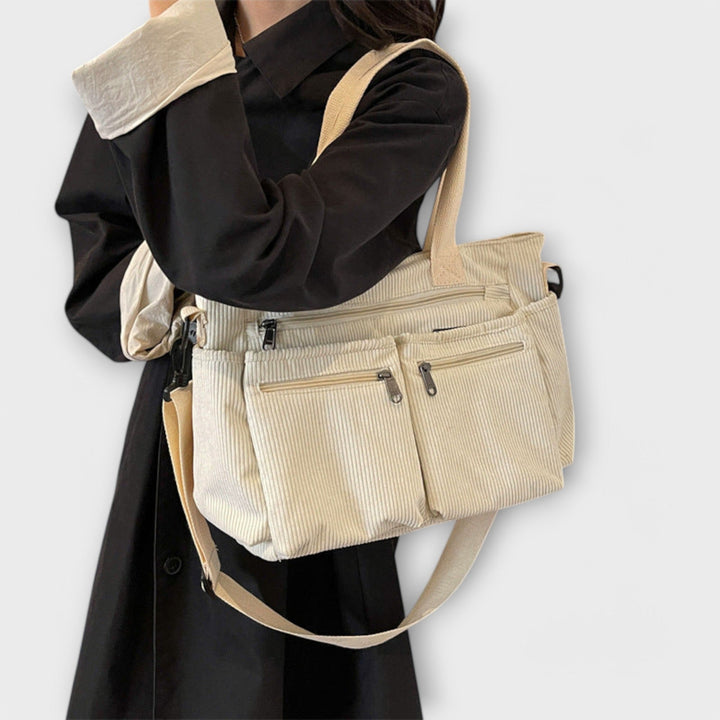 Borsa tote Iris nera, appesa a un appendiabiti, mostrando il suo profilo sottile quando non è piena.