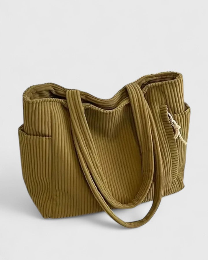 Borsa tote Isabel color mostarda, posata su una superficie, con attenzione al materiale e alla finitura.