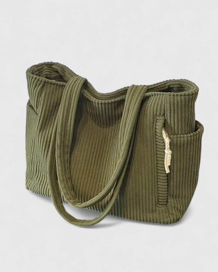 Borsa tote Isabel verde indossata a spalla da una modella, in un contesto urbano, per mostrare le dimensioni.