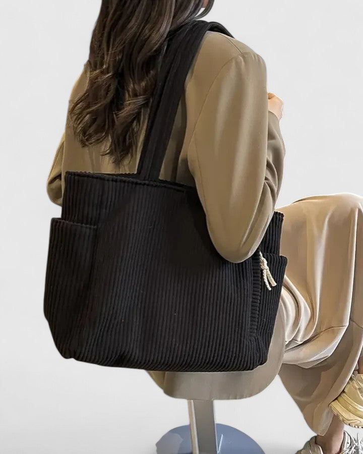 Borsa tote Isabel bianca appoggiata su un tavolo, accanto a un laptop e altri oggetti personali, per illustrarne l'uso.