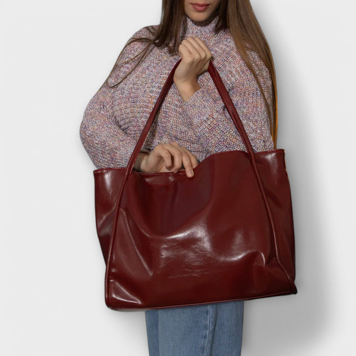 Borsa Isabelle rossa appoggiata su una scrivania in un ambiente lavorativo, che mostra la sua versatilità.