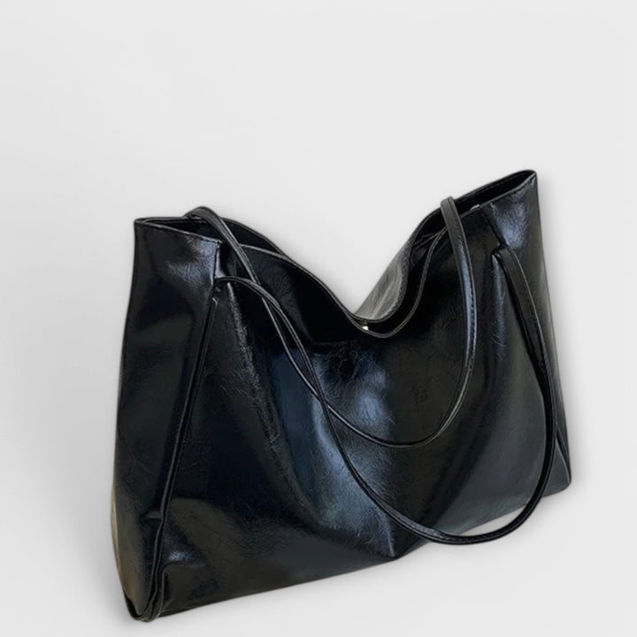 Modella che indossa la borsa tote Isabelle nera a spalla, in un contesto casual da passeggio.