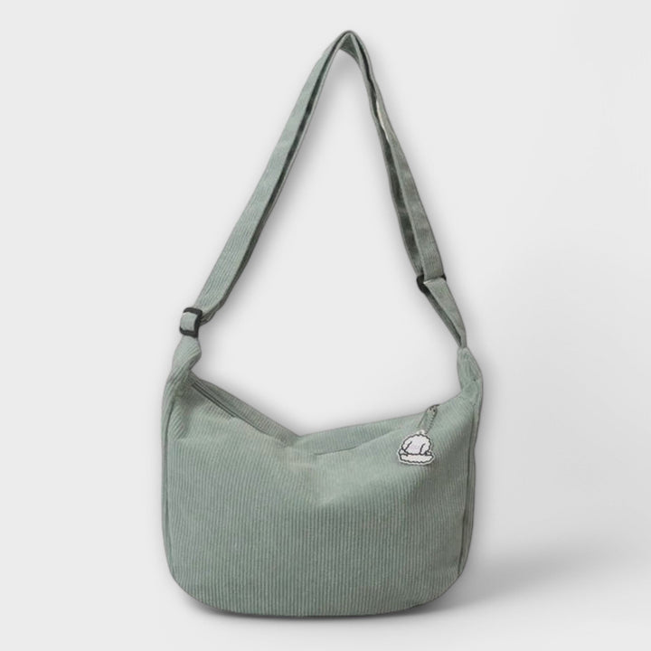 Borsa a spalla resistente in un contesto di shopping, appoggiata su un banco di un caffè.