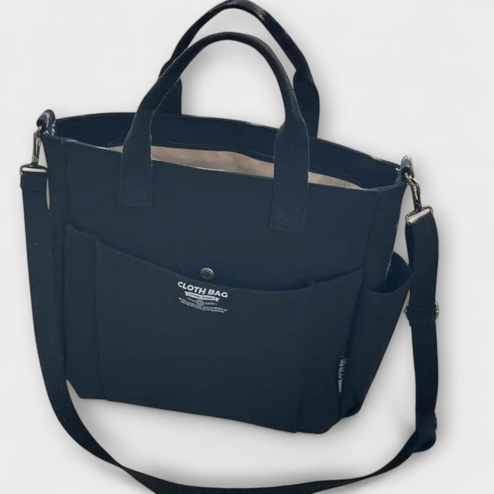 Donna che indossa la borsa tote versatile Maia nera a tracolla, in un contesto urbano.