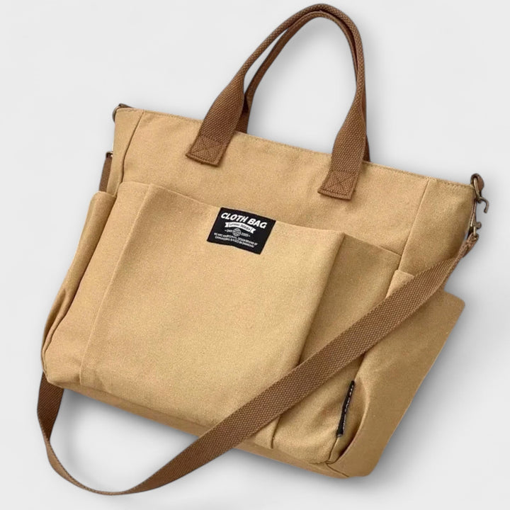Tre borse tote versatili Maia nei colori khaki, bianco e nero, allineate su sfondo neutro.