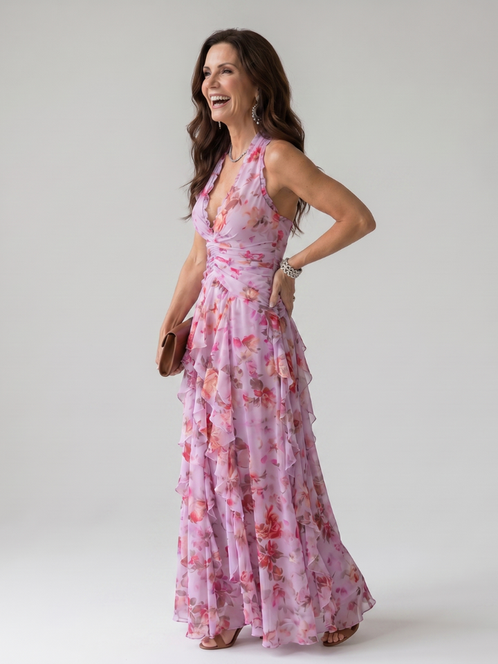Dettaglio del corpetto arricciato e dello scollo halter dell'abito lungo floreale in tonalità rosa.