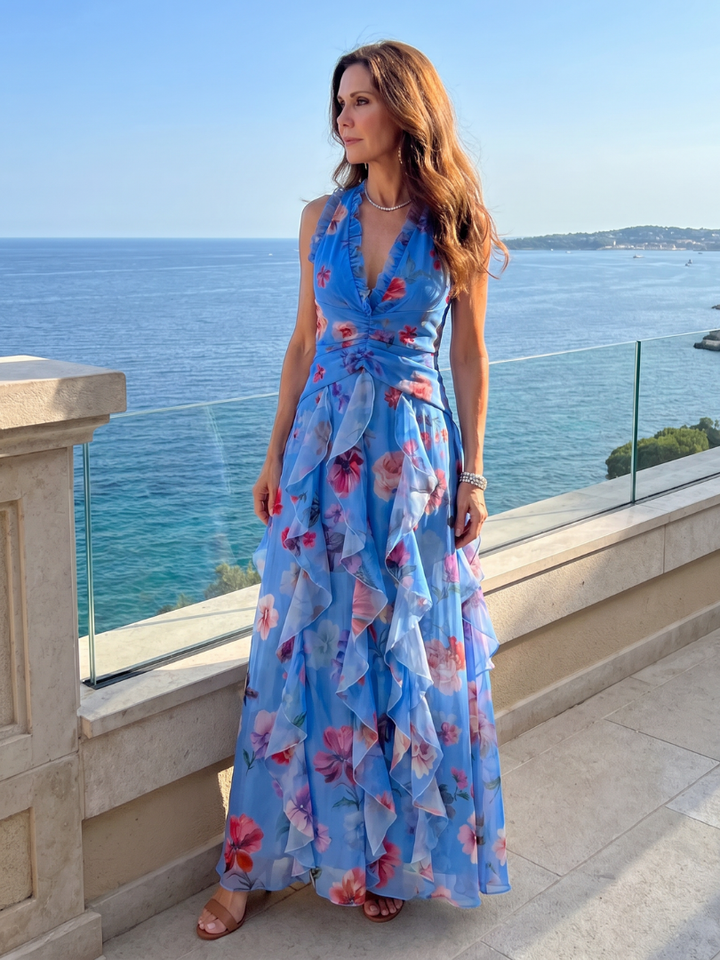 Modella seduta, che mostra la comodità e l'eleganza dell'abito lungo floreale blu in un contesto rilassato.