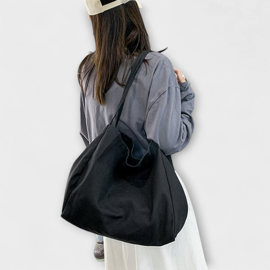 Borsa shopper in tela marrone, dettaglio della texture del tessuto e cuciture robuste, con manici resistenti.