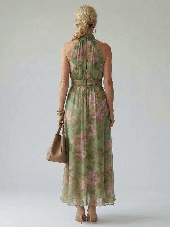 Vista posteriore dell'abito midi halter verde salvia, con la modella che cammina, mostrando il movimento arioso del capo.
