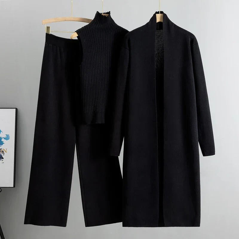 Modella in un set abiti donna a tre pezzi nero, vista laterale, che evidenzia la caduta fluida del cardigan e dei pantaloni.