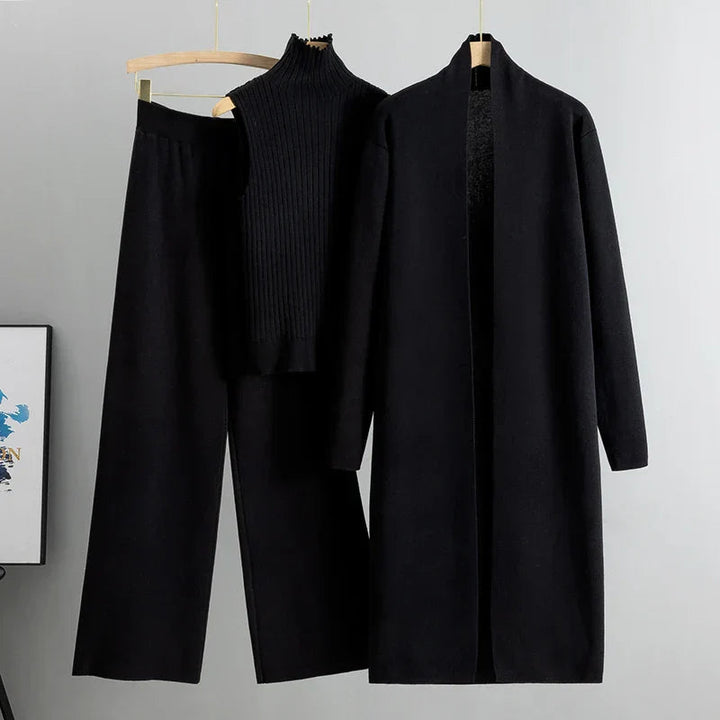 Modella in un set abiti donna a tre pezzi nero, vista laterale, che evidenzia la caduta fluida del cardigan e dei pantaloni.