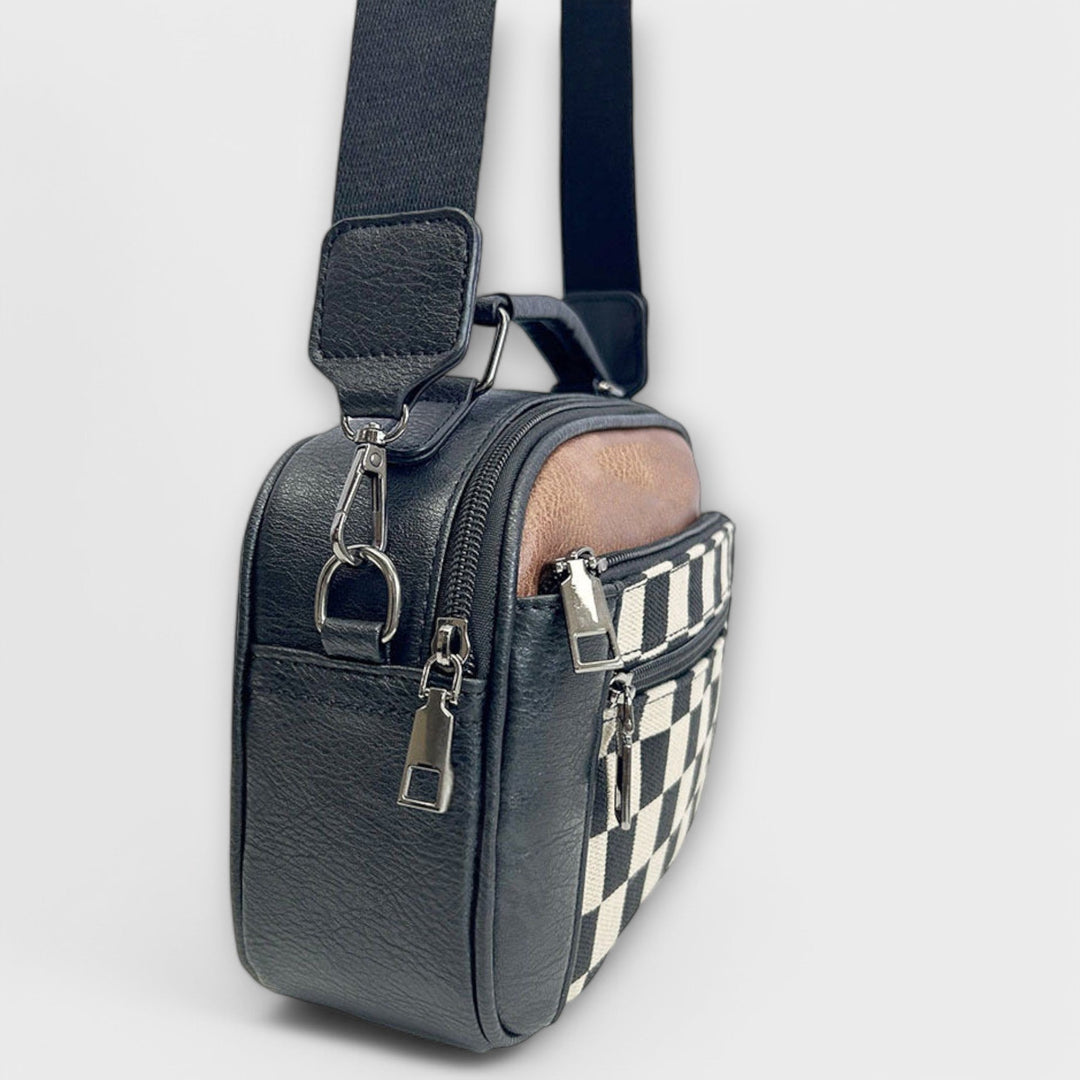 Donna che indossa la borsa a spalla Talia nera in un contesto urbano, mostrando la versatilità del design.